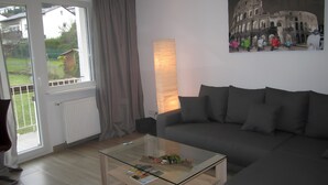Ein modernes Wohnzimmer mit einem Glastisch, einem grauen Sofa und einem Gemälde des Kolosseums.