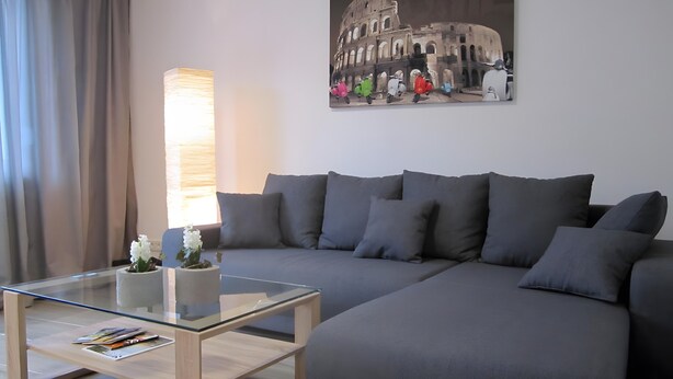 Ein modernes Wohnzimmer mit einer Couch, einem Glastisch, einer Lampe und einem Gemälde des Kolosseums.