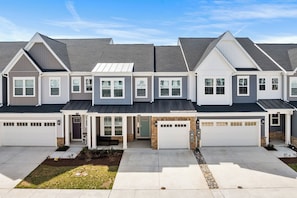A row of townhouses with attached garages, a covered entryway, and a well-maintained front lawn. - 31214 Mimi lane (Frankford)