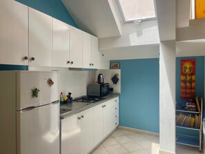 A compact kitchen with white cabinets, a gas stove, and a microwave. - Casetta Alida | Bright Central Loft with Starling & A/C (Santa Maria)