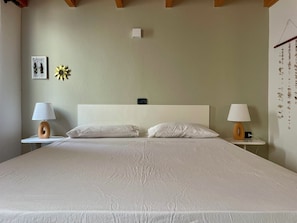 A neatly made bed with two pillows and two bedside tables, each with a lamp. - Casetta Alida | Bright, centrally located loft with a view of the stars and air conditioning   (Santa Maria)