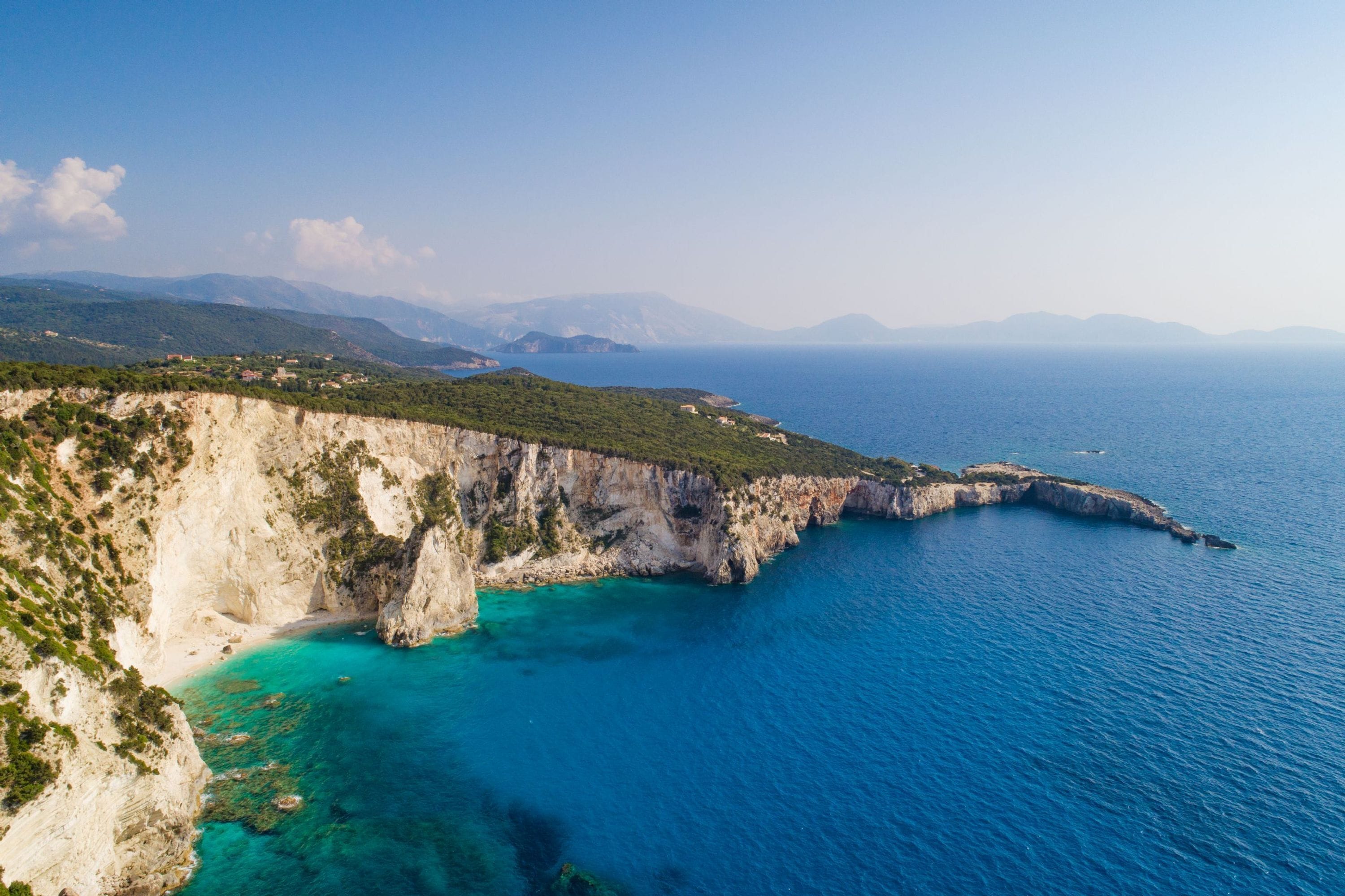 A coastal landscape with cliffs and clear blue sea.