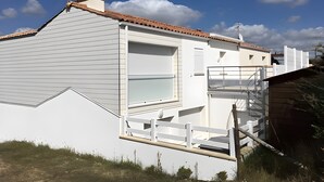 Een wit gebouw met een groot raam, een balkon en een trap naar een terras.