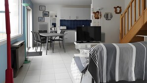 Een moderne keuken met witte kasten, een blauwe achterwand en een flatscreen televisie.