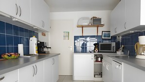 Een moderne keuken met witte kasten, een magnetron, een broodrooster en een koffieapparaat.
