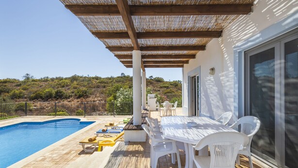 A poolside area with a pergola, outdoor seating, and a view of the landscape. - Villa Nina With 4 Bedrooms and 4 Bathrooms (Olhao)