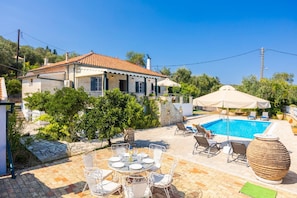 Ein Haus mit Swimmingpool, Sitzgelegenheiten im Freien und einem gepflasterten Weg.