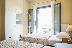 Une chambre avec deux lits, une armoire, une fenêtre avec des rideaux et une vue sur l’extérieur.