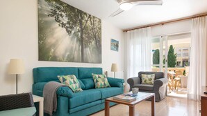 A living room with a teal sofa, a coffee table, and a painting of trees. - Villa El Olivo With 3 Bedrooms and 3 Bathrooms (Pollença)