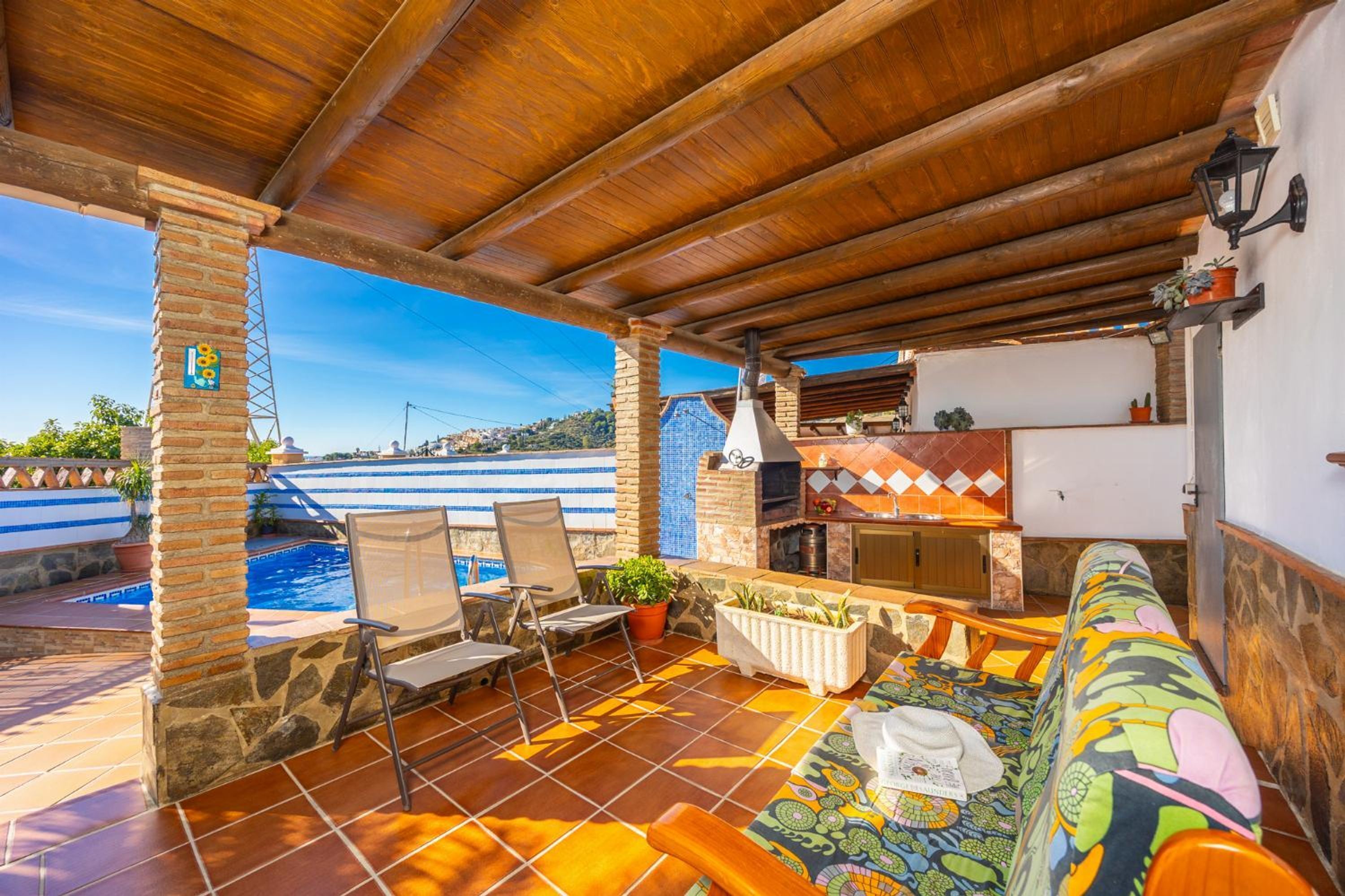 Eine überdachte Terrasse mit Pool, Sitzgelegenheiten im Freien und Grillplatz.