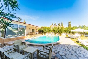 Una piscina con sillones de descanso y un patio de piedra.