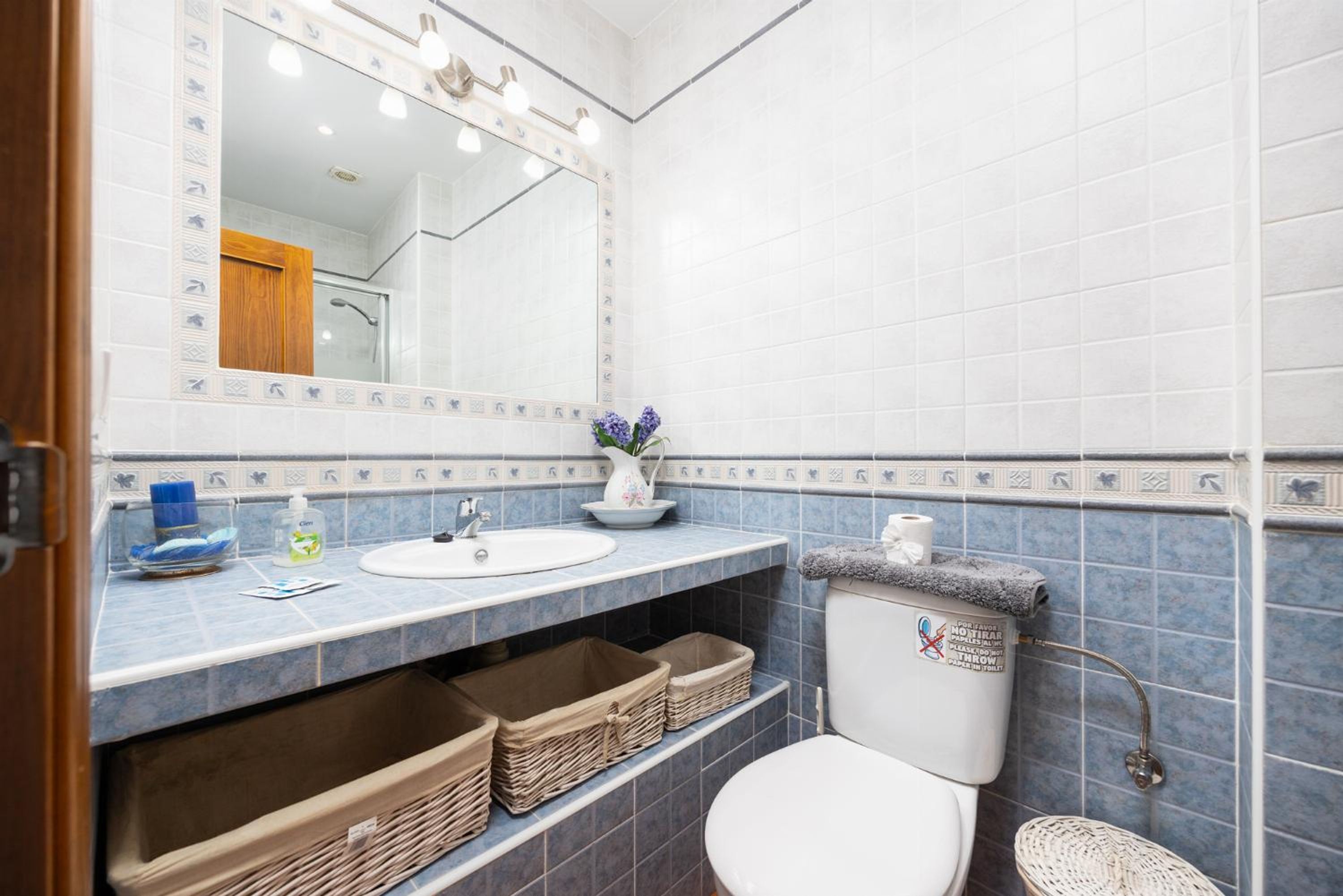 Een badkamer met een wastafel, spiegel en toilet.