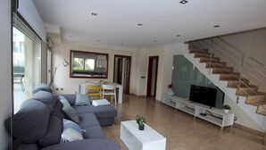 Ein modernes Wohnzimmer mit grauem Sofa, einem weißen Couchtisch und einem Fernsehgerät auf einem weißen Schrank.