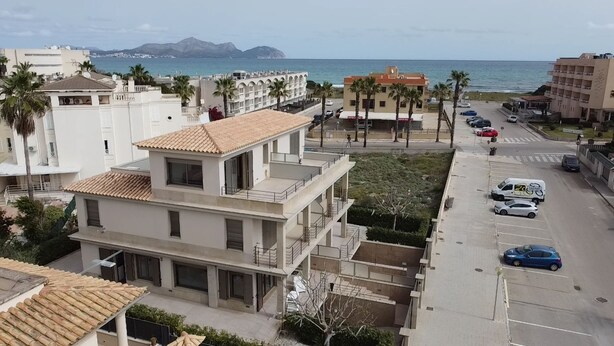 Ein mehrgeschossiges Gebäude mit Balkonen, einem Parkplatz und Blick auf das Meer.