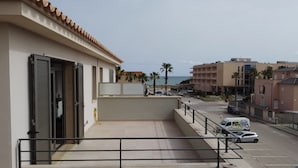 Ein Balkon mit Meerblick, ein Parkplatz und Gebäude im Hintergrund.