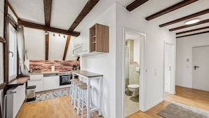 A compact kitchen with wooden accents, a bar stool seating area, and a visible bathroom. - Ramoni Apartments - Enzzauber - Bad Wildbad (Bad Wildbad)