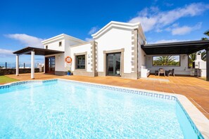 Ein modernes Haus mit Swimmingpool, einer überdachten Terrasse und Blick auf den Ozean.