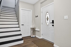 A staircase leading to a door with a decorative glass panel, a small shelf, and a trash can. - 2 Minutes Walk to the BEACH (Norfolk)