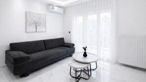 Uma sala de estar moderna com um sofá cinzento, uma mesinha redonda e um radiador branco.