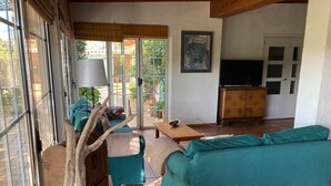 Uma sala de estar com sofá, mesa, armário e televisão.