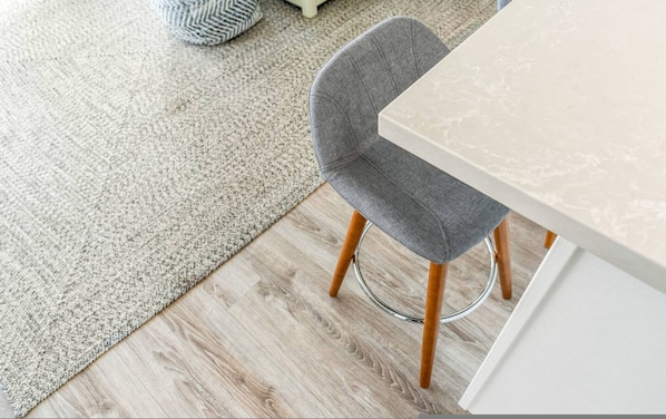 A dining area with a chair, a table, a rug, and wooden flooring. - Waterfront 1BR Modern Condo Friday Harbour (Innisfil)