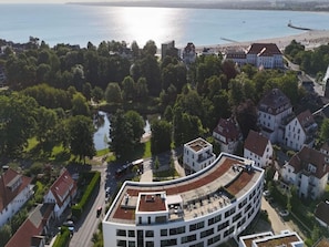 A modern building with a curved roof, surrounded by residential houses and a body of water. - 4 Star Holiday Home in Travemunde (Lübeck)