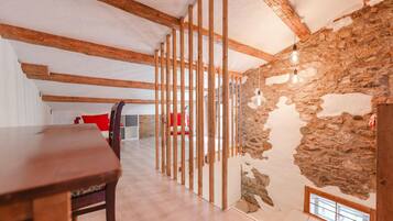 Ein Innenraum mit freiliegenden Holzbalken, einer Steinwand und einem Holztisch.
