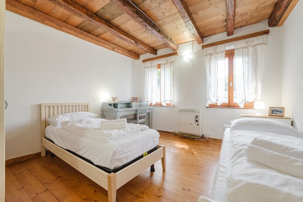 Une chambre avec un plafond en bois, un lit, un bureau et un radiateur.