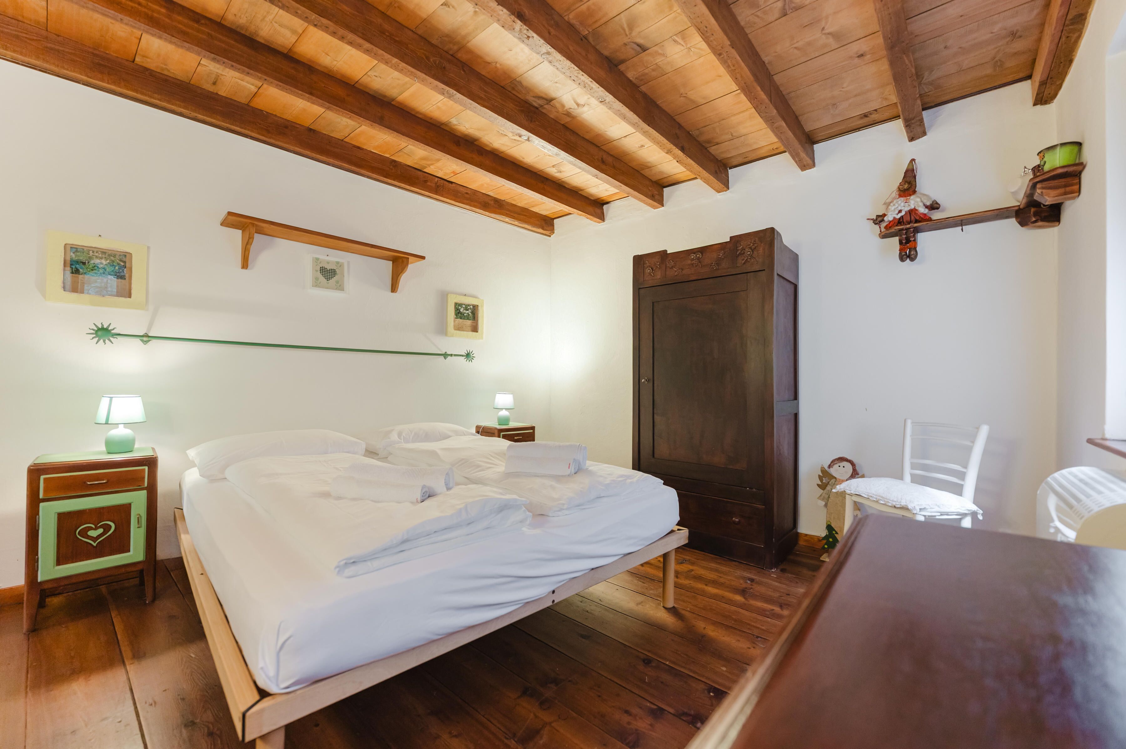 Une pièce comprenant un lit en bois, une armoire, une petite table et une chaise.