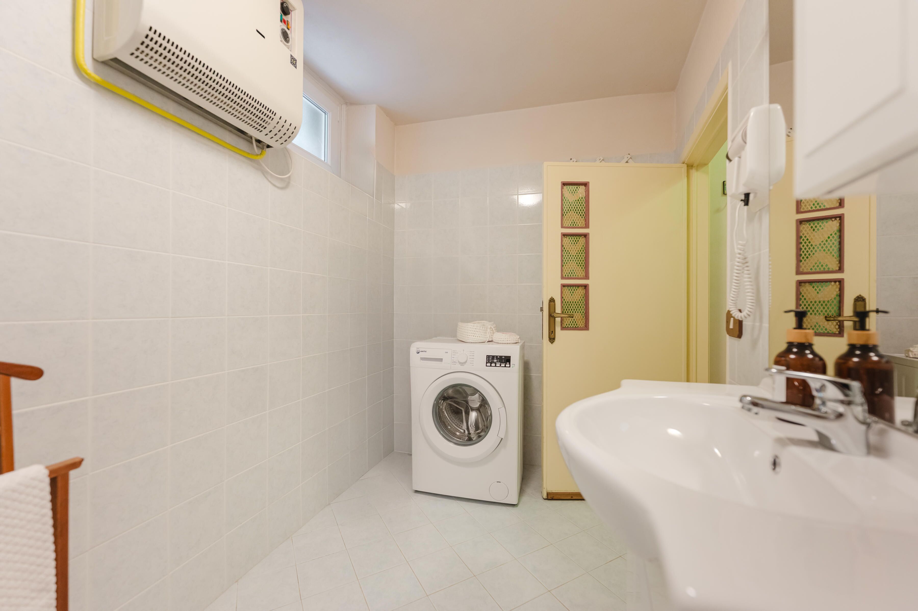 A compact bathroom with a washing machine, a sink, and a toilet.