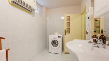 A compact bathroom with a washing machine, a sink, and a toilet.