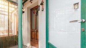 Un couloir avec une porte en bois, une porte verte et un paillasson à motifs à l’entrée.