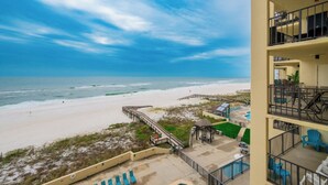 Un hotel frente a la playa con piscina, sillas de descanso y vista al océano.