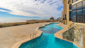 Zona de piscina con vistas al océano, un pabellón y un edificio con amplios ventanales.