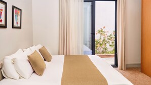 Et hotelværelse med en seng, et vindue med gardiner og udsigt til en have.