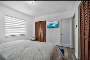 A bedroom with a bed, a TV, a wardrobe, and a window with blinds. - Cozy house in the heart Of Miami (Miami)