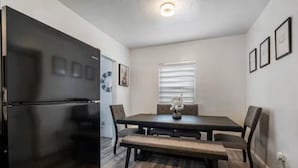 A compact kitchen with a built-in refrigerator, a dining table with chairs, and a bench. - Cozy house in the heart Of Miami (Miami)