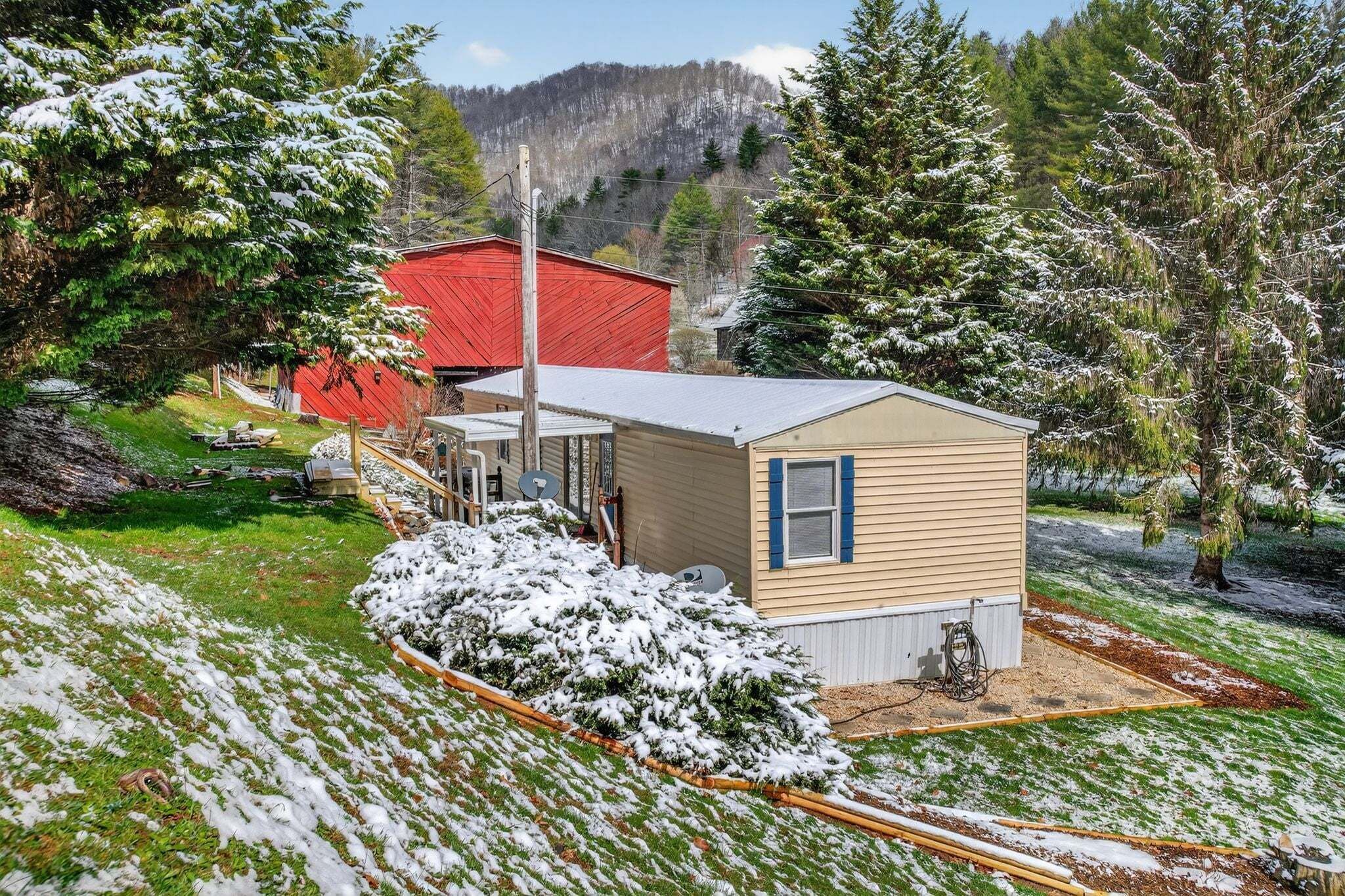 A small, single-story building with a red roof, surrounded by snow-covered trees and a hilly landscape.