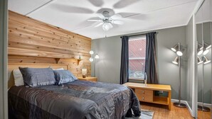 A bedroom with a bed, bedside tables, a desk, a ceiling fan, and a window with curtains. - Peaceful Pines - 2br Getaway Near Blue Ridge 2 Bedroom Home (Burnsville)