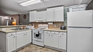 A kitchen with white cabinets, a stove, a sink, and a refrigerator. - Peaceful Pines - 2br Getaway Near Blue Ridge 2 Bedroom Home (Burnsville)
