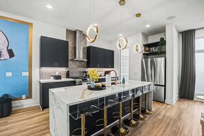 Una cocina moderna con una isla central, taburetes de bar e iluminación colgante.