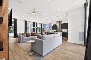 Una sala de estar moderna con un sofá gris, una mesita redonda y un ventilador de techo.