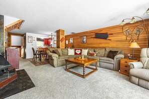 Ein Wohnzimmer mit einer Holzwand, einer Couch, einem Couchtisch und einem Kamin.