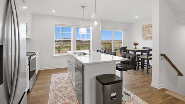 A modern kitchen with a central island, stainless steel appliances, and a dining area with a view. - New 4br Townhome Near Harpers Ferry 4 Bedroom Townhouse (Charles Town)