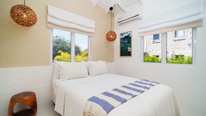 A bedroom with a bed, two windows, a hanging light, and an air conditioning unit. - Haynes House 5 Bedroom Home (Holetown)