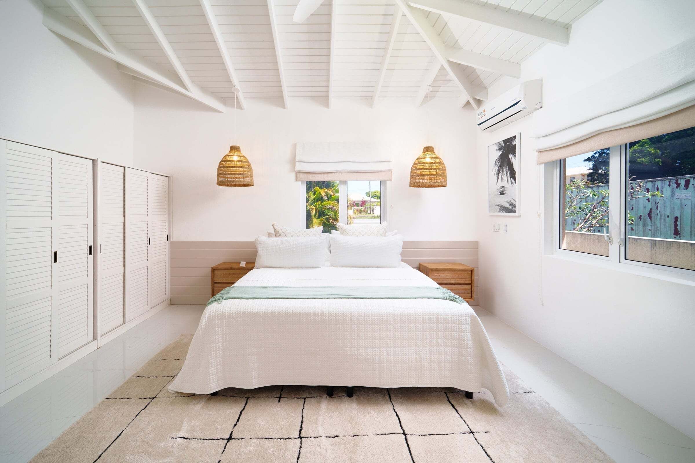 A bedroom with a bed, bedside tables, a window with a view, and a ceiling fan.
