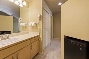 A bathroom with a sink, mirror, hair dryer, and a trash bin. - River Ridge 429b 1 Bedroom Studio (Bend)