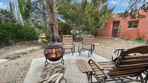 A patio with a fire pit, wooden benches, and a concrete floor. - Casita Adobe Duplex (Grand Junction)