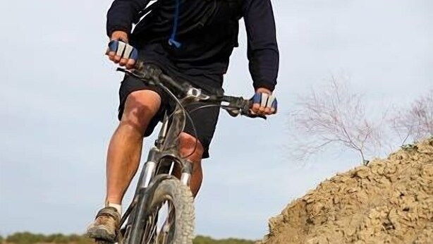 A person riding a mountain bike on a dirt trail. - Casita Adobe Duplex (Grand Junction)