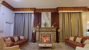 Een woonkamer met een open haard, twee banken, een salontafel en een kamerkleed met een patroon.